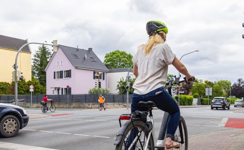 Eine Radfahrerin fährt auf dem Radweg bei Grün über eine Kreuzung.