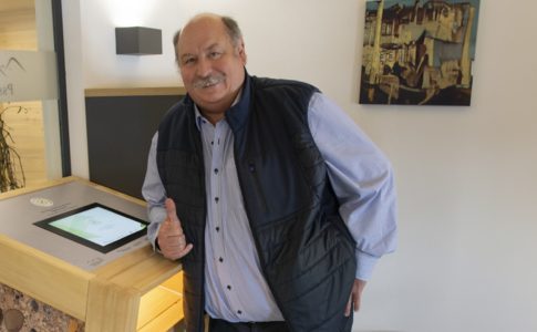 Mann, der vor einem Anmeldeterminal mit Tablet steht.