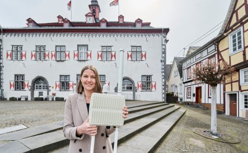 Projektleiterin und Citymanagerin Karin Wessel vor dem Rathaus von Linz am Rhein mit LoRaWAN-Funkantenne in den Händen.