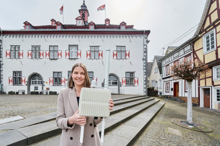 Projektleiterin und Citymanagerin Karin Wessel vor dem Rathaus von Linz am Rhein mit LoRaWAN-Funkantenne in den Händen.