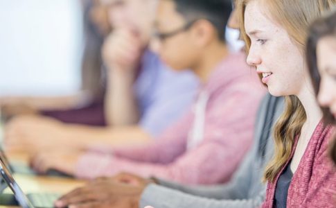 Schülerinnen und Schüler arbeiten an Laptops.