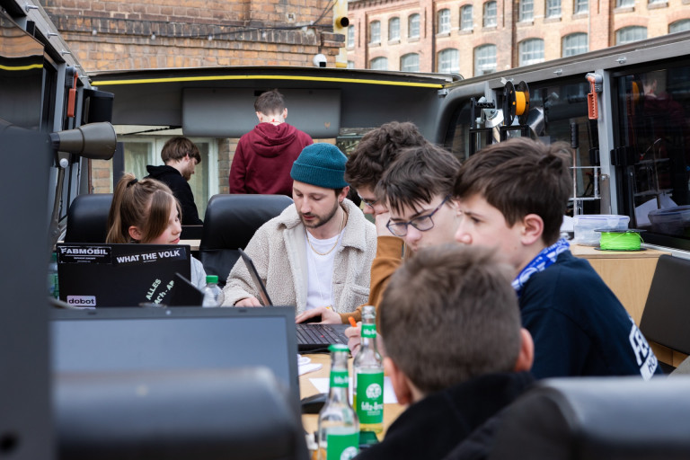 Kinder sitzen in einem Workshop des Fabmobils auf dem Oberdeck des Doppeldeckerbusses.