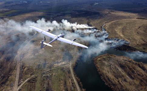 Drohne fliegt über eine Landschaft, von der Rauch aufsteigt