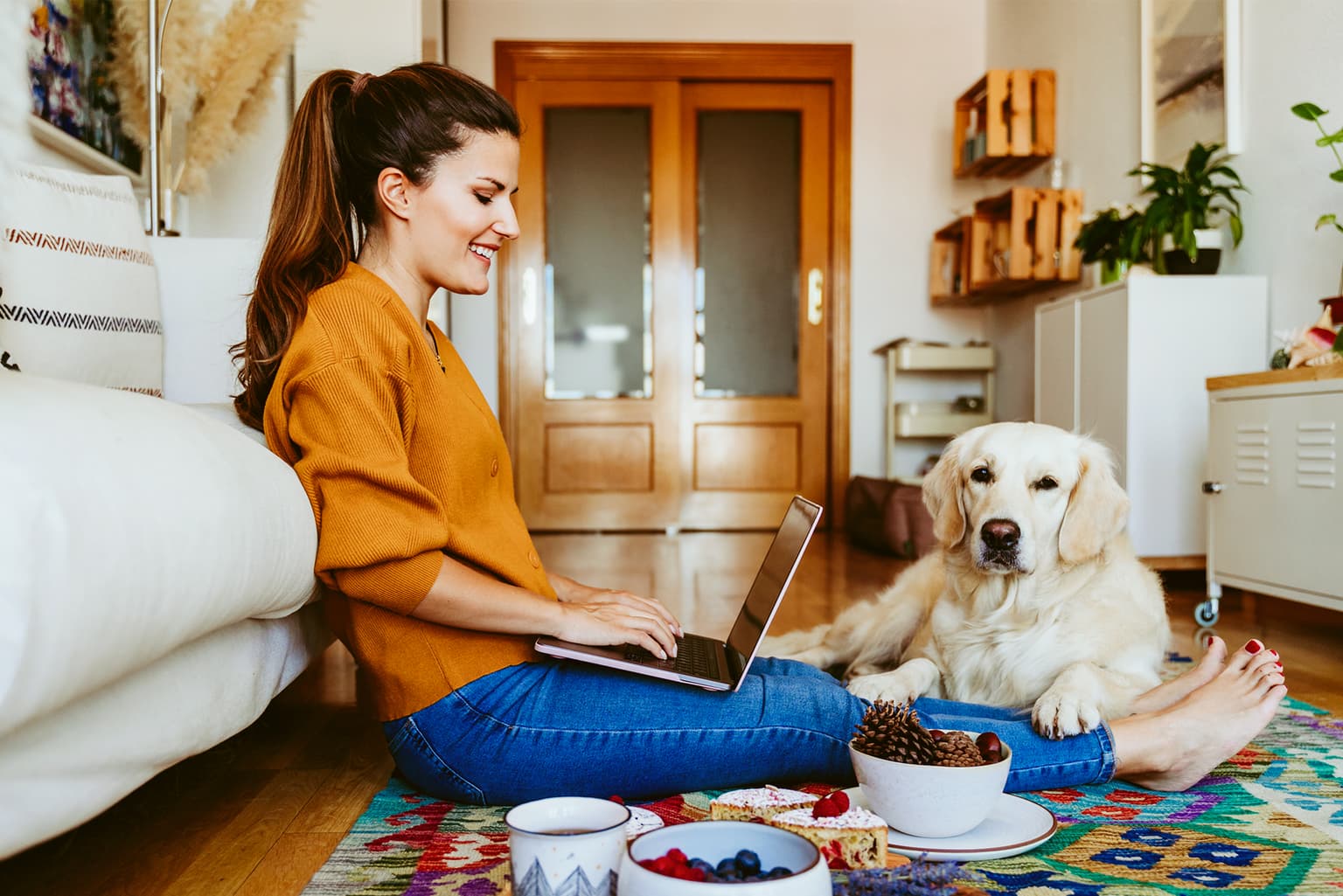 Eigentümer - Frau sitzt auf dem Boden mit Hund und arbeitet am PC 2