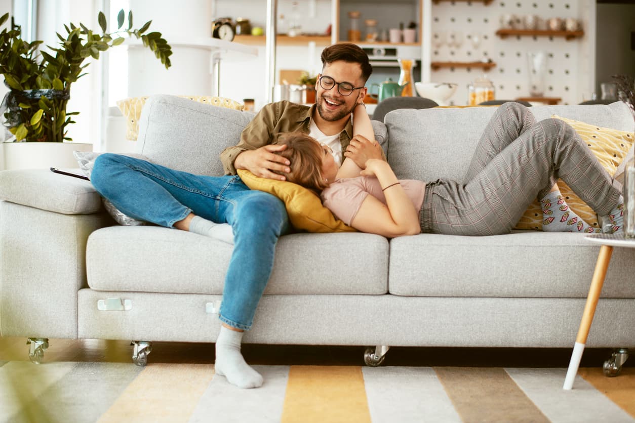 Mieter - Paar liegt auf der Couch und umarmen sich